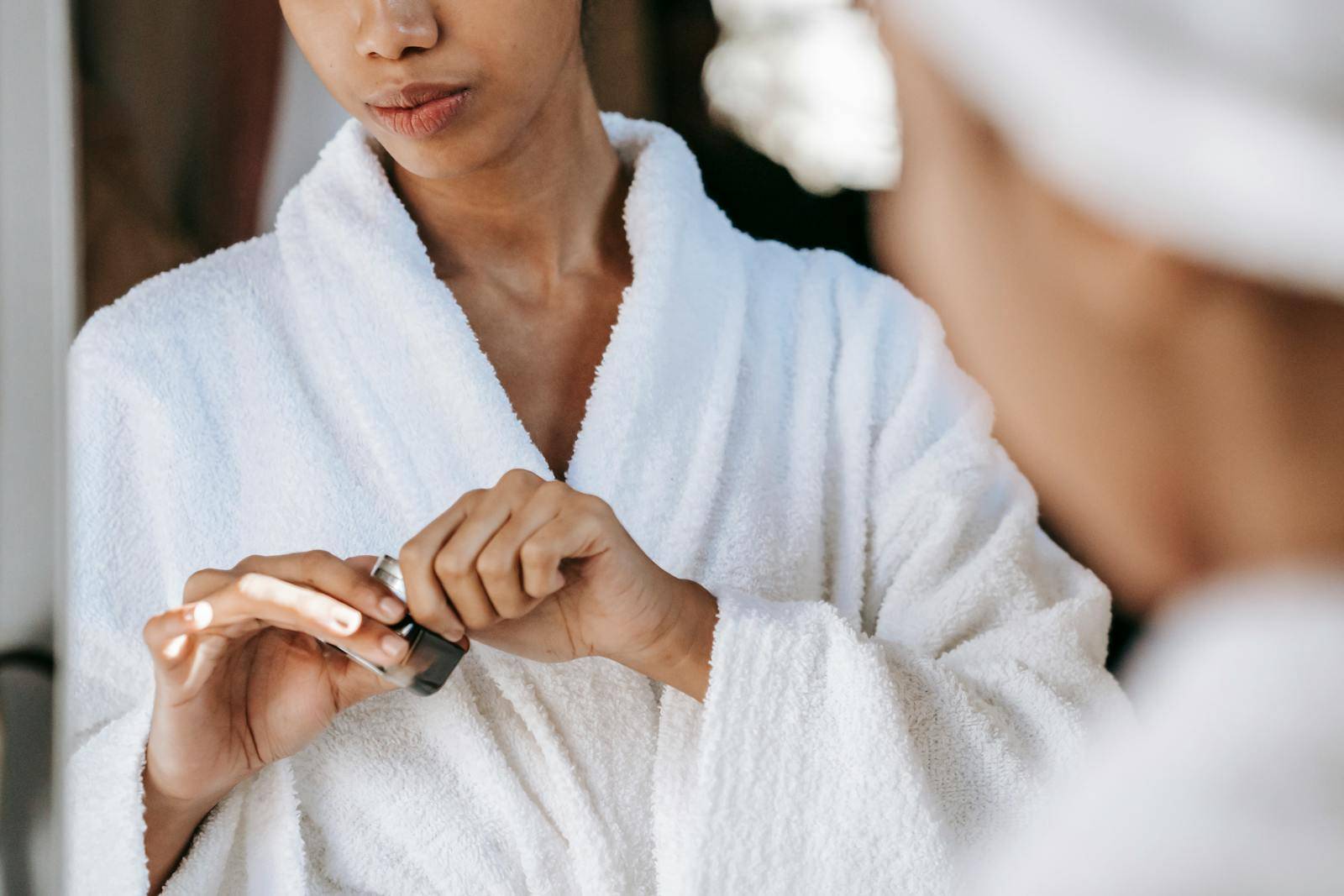 Black woman applying lotion on face